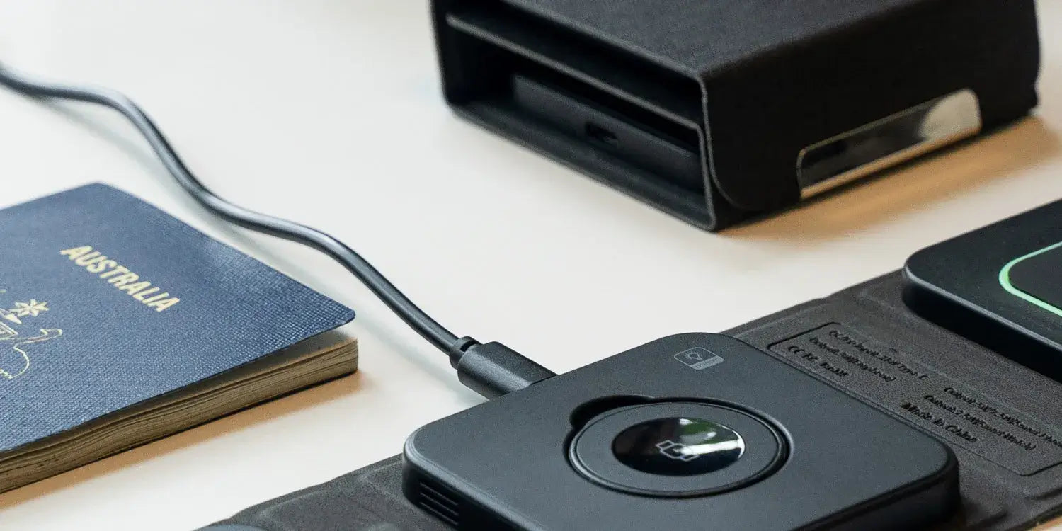 Close-up of the Cubica 3-in-1 travel charger by Modern Standard, showcasing its compact design alongside a passport and travel essentials.