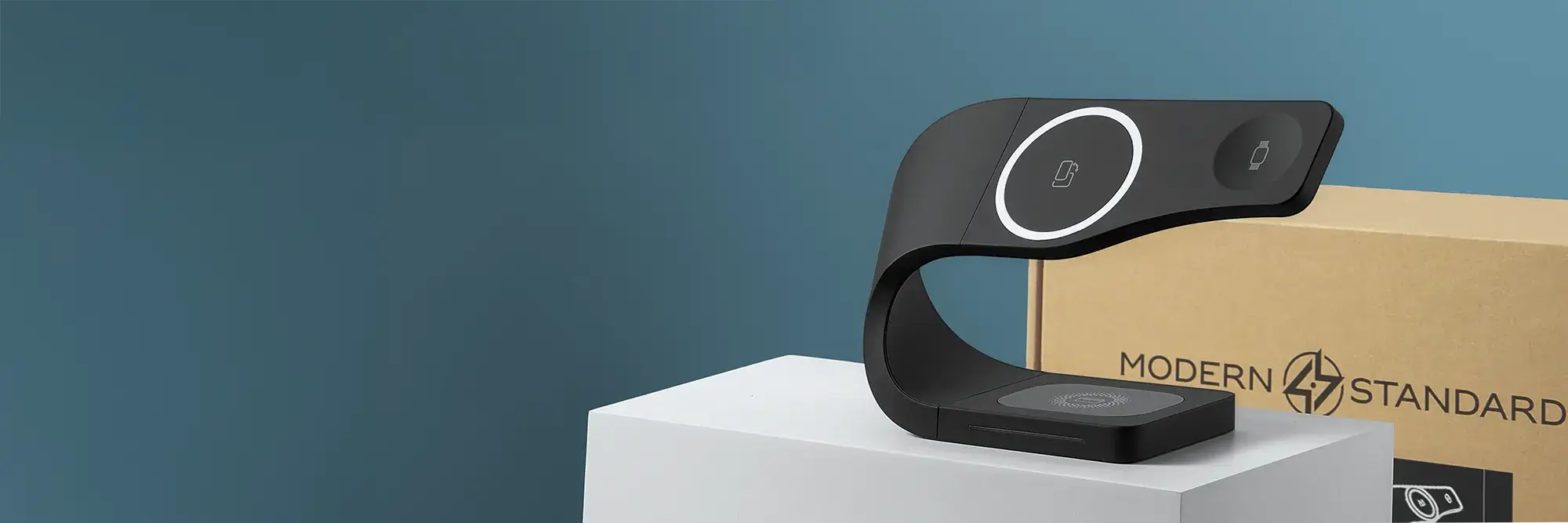Black SIMPLI MagSafe charging stand on white pedestal with Modern Standard branded box in background