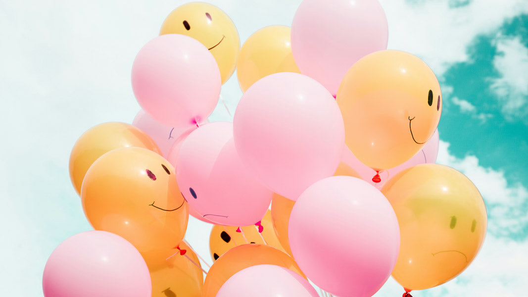 Bright pink and yellow balloons with smiley faces floating against a blue sky, symbolizing customer satisfaction and a positive refund policy experience.