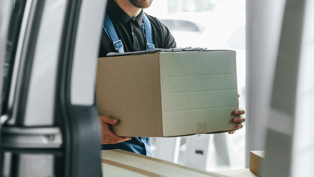 Delivery person handling a cardboard box, representing zero cost return policy for hassle-free customer returns, highlighting commitment to customer satisfaction and convenience.