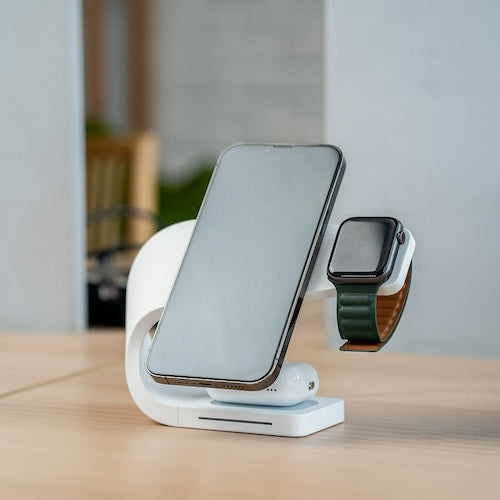 SIMPLI MagSafe charging station on a desk, efficiently powering an iPhone, Apple Watch, and AirPods simultaneously, featuring sleek white design for modern workspace.